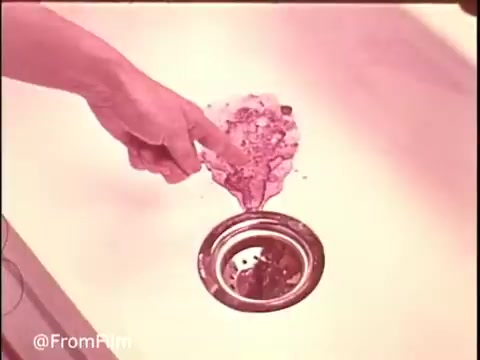 In this 16mm still from a 1970s Ajax Cleanser commercial, we see a hand pointing at a sink with a pile of cleaning powder that is likely Ajax. The commercial emphasizes the product's effectiveness by showcasing its ability to 'turn blue' and 'power out stains.' The visual suggests a practical demonstration of the cleanser in action, appealing to viewers looking for effective cleaning solutions.   Follow along for more nostalgic commercials @FromFilm!