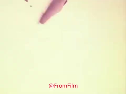 The still from the 1976 trailer for 'Drive-In' features a muted color palette, with a focus on an abstract shape, possibly representing an object or a gesture. The image conveys a sense of nostalgia and simplicity, reflecting the era's film style, likely evoking curiosity about the movie’s themes or plot. The presence of a watermark suggests it's a shared or preserved frame from the original film.