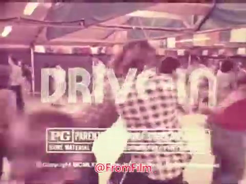 The still from the 1976 movie trailer for 'Drive-In' showcases people enjoying a lively atmosphere, likely at a drive-in theater. The title 'DRIVE-IN' is prominently displayed in bold letters, indicating the focus of the film. A PG rating is visible, suggesting it contains some material that may not be suitable for younger viewers. The overall aesthetic evokes a nostalgic vibe typical of 1970s cinema.