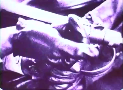 The still from 'The Laughing Policeman' trailer features a close-up shot of a hand gripping a police baton or gun, indicative of the film's crime and police themes. The monochromatic tones of the 16mm print suggest a vintage look, enhancing the gritty atmosphere associated with the narrative. The focus on the hand implies action or tension, characteristic of the film's suspenseful elements.