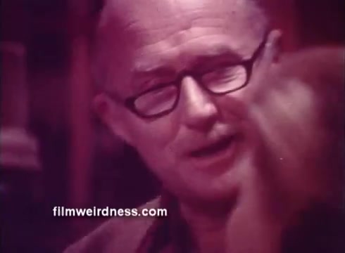 The still features a middle-aged man with glasses, likely a spokesperson, smiling and engaging with an unseen individual. The overall look is vintage, characteristic of 1970s commercials, with warm color tones. The context suggests it's promoting Ben Gay, a topical analgesic known for providing warmth and relief. The friendly demeanor of the man contributes to a comforting atmosphere, typical of product endorsements from that era.