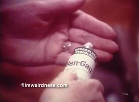 The still features a hand applying Ben Gay ointment, with the tube prominently displayed. The scene emphasizes the product's use for relief, capturing the tactile experience of using the topical treatment. The visual conveys a warm, inviting atmosphere typical of 1970s commercials.