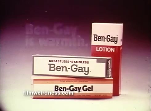 The still features three products from the Ben Gay line, prominently displaying the logo and packaging of Ben Gay lotion and gel. The backdrop is softly illuminated, highlighting the text 'Ben Gay is warmth,' which suggests the comforting and soothing qualities of the products. The overall aesthetic is characteristic of 1970s advertising, emphasizing simplicity and clarity in product presentation.