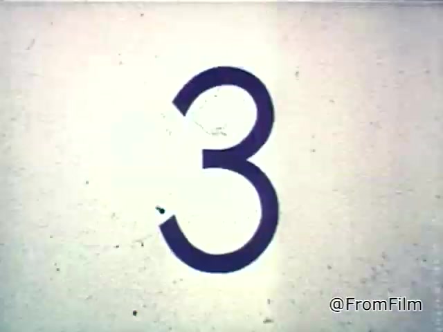 The still features a large number “3” prominently displayed against a faded, textured background, typical of mid-20th century film aesthetics. This likely indicates a countdown, common in film and television, preceding a scene or advertisement. In the context of the Chef Boyardee spaghetti sauce commercial from the 1960s, this visual element sets the stage for presenting the product and its quality, aligned with the voice-over emphasizing the importance of choosing good ingredients. The overall look evokes a nostalgic ambiance, indicative of the era's advertising style.