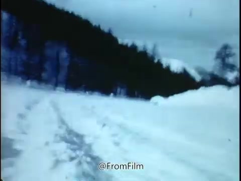 The still from the 1968 National Safety Council PSA depicts a winter scene characterized by snow-covered roads surrounded by pine trees. The image conveys a sense of coldness and potential danger, emphasizing the risks associated with driving in such conditions. The mention of 'the trap lies concealed' suggests that the snowy landscape masks hazards that could lead to accidents, particularly for those who are unaware of their surroundings or driving conditions. This aligns with the broader message of the PSA, which warns about the importance of tire wear and pressure, encouraging drivers to remain vigilant and cautious. The overall tone of the still, combined with the context provided, reflects a serious reminder about road safety during adverse weather conditions.