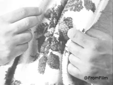 The still features hands holding a towel with a distinctive pattern. The towel appears to showcase the softness and quality likely emphasized in the Breeze Detergent commercial from the 1960s. Breeze was marketed as a soapless cleansing agent, highlighting its effectiveness for washing laundry. This promotion may imply incentives, such as receiving a towel for using Breeze detergent, a common marketing tactic during that era.