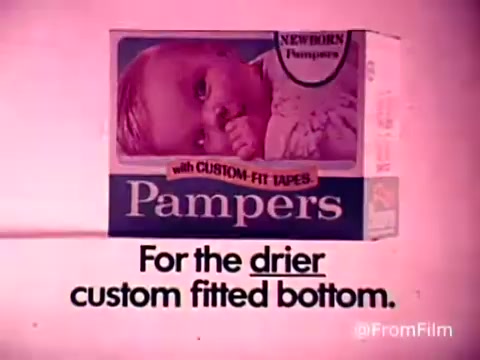 The still features a vintage Pampers diaper box prominently displayed against a pink background. The packaging highlights its suitability for newborns, with the phrase 'with CUSTOM-FIT TAPES' emphasizing comfort and adjustability. Below the box, a tagline reads, 'For the drier custom fitted bottom,' promoting the product's benefits for parents. The overall aesthetic reflects the 1970s advertising style.