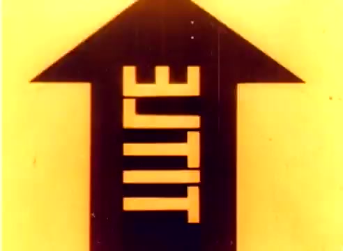The still features a bold graphic design, showcasing a large black arrow pointing upwards with the word 'LITE' written inside it. The background is a warm yellow, likely a reflection of the film's era. This still serves as a promotional visual from the Kodak 1977 Sales Film featuring Michael Landon and Dick Van Dyke, aimed at highlighting Kodak's products for the Christmas season. The overall aesthetic captures the vibrant and optimistic tone of the late 1970s.