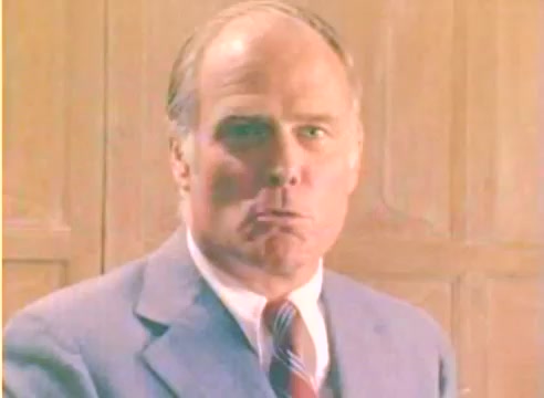 The still depicts a middle-aged man in a suit with a serious expression, likely portraying an important character or situation. The background features wooden paneling, indicating a formal or professional setting. The silent film nature of the image suggests it captures a moment of significance, potentially setting the tone for a Christmas sales message from Kodak in 1977. The overall color and composition evoke a nostalgic feel typical of that era.