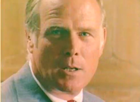 The still from the 'Kodak 1977 Sales Film' presents a close-up of a man in a suit with a serious expression. The color palette is warm, typical of the era. The focus seems to be on conveying a message or promotion, aligning with the film's purpose of showcasing Kodak's offerings for the upcoming Christmas season. Without sound, the visual emphasizes the man's engagement and intent.