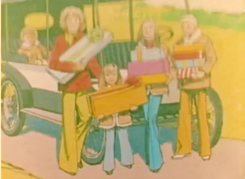 The still from the 'Kodak 1977 Sales Film' features a cheerful scene with four individuals—two adults, a young girl, and a child—gathered beside a vintage car. They are dressed in 1970s fashion, holding colorful wrapped presents, suggesting a festive atmosphere. The backdrop features a vibrant and sunny landscape, enhancing the joyful theme associated with the Christmas season. The film captures a nostalgic depiction of holiday spirit.