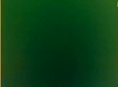 The still from the 'Kodak 1977 Sales Film' features a color negative that appears to be primarily a solid green hue, possibly indicating a test or blank frame. Given its context as a silent workprint, it likely serves to showcase Kodak's film capabilities during the 1977 Christmas season, highlighting the work of Michael Landon and Dick Van Dyke. The absence of visual details suggests a focus on the film medium rather than specific content.