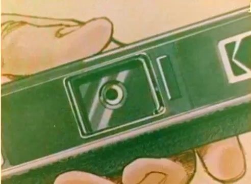 The 16mm still from the 'Kodak 1977 Sales Film' features a close-up of a hand holding a Kodak camera. The camera's lens and branding are prominently displayed. This silent color negative emphasizes the brand's product, aligning with the promotional theme leading up to the 1977 Christmas season. The overall aesthetic is consistent with mid-1970s design, showcasing Kodak's focus on photography and family moments during the holidays.