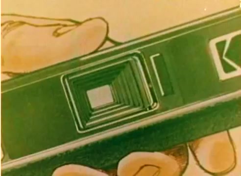 The still from the 'Kodak 1977 Sales Film' features a close-up view of a hand holding a Kodak camera. The image showcases the camera's lens, emphasizing its depth and design. The visual quality reflects the vibrant colors characteristic of Kodak's film stock. This silent workprint serves as a promotional piece leading into the Christmas season, highlighting Kodak's products in a festive context.