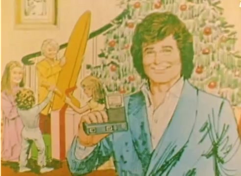 The still from the 'Kodak 1977 Sales Film' features an animated or illustrated depiction of Michael Landon smiling and holding a camera. In the background, two children and an adult are interacting with a large, colorful surfboard and a Christmas tree adorned with decorations. The overall scene conveys a festive, family-oriented theme, suitable for promoting Kodak products during the holiday season.