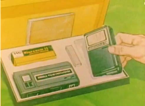 The still from the 'Kodak 1977 Sales Film' shows a hand reaching for a small device from an open box. Inside the box are various Kodak products, including a cassette and a Yellow battery. The vibrant colors and layout suggest a promotional context, aiming to highlight Kodak's offerings for the 1977 Christmas season. The overall tone is informative and engaging, typical of sales films from that era.