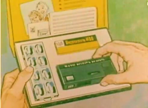 The 16mm still features an animated depiction of hands opening a colorful Kodak sales box. The box contains a film cartridge and several film reels, likely illustrating the company's offerings for the 1977 Christmas season. The scene emphasizes Kodak's focus on family moments and memories, as inferred from the imagery. The overall tone conveys festive anticipation and innovation in photography.