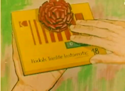 The 16mm still from the 'Kodak 1977 Sales Film' features a brightly colored scene with hands presenting a Kodak film box adorned with a decorative ribbon. The box is labeled 'Kodak Trimlite Instamatic 18.' The background is softly painted, suggesting a festive, Christmas theme to promote Kodak products during the holiday season. The overall tone is cheerful and inviting, capturing the excitement of giving gifts related to photography.