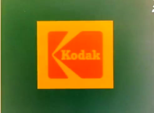 The still features the iconic Kodak logo on a green background, indicative of the company's branding during the 1970s. This is part of a silent color negative from their 1977 sales film, which likely promotes Kodak products in the lead-up to the Christmas season. The film includes appearances by celebrities Michael Landon and Dick Van Dyke.