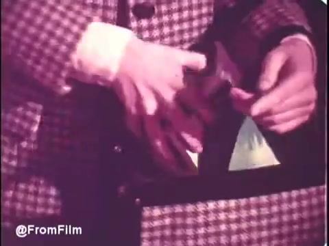 The still from the 1970s Puff's Tissues commercial features a close-up of a man’s hands as he reaches into a stylish, patterned bag. The focus is on the colors and textures, highlighting the tissues being showcased. The vibrant tones hint at the product's availability in blue and green. The vintage aesthetic of the 16mm print adds a nostalgic feel to the scene.