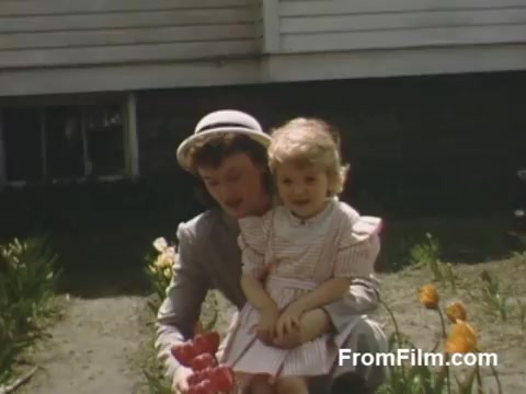 This 16mm still from 'The Tulip Film' captures a charming moment in Holland, Michigan, before the Tulip Time Festival. The Kodachrome footage beautifully portrays a woman and a young girl together in a flower garden, surrounded by vibrant tulips. The scene reflects the warmth of post-war America, highlighting the innocence of childhood amidst blooming flowers.