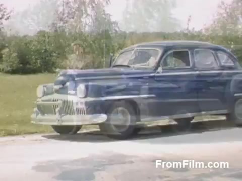 This 16mm still from 'The Tulip Film' showcases post-war Kodachrome footage, likely capturing the early days of flower cultivation in Holland, Michigan, prior to the Tulip Time Festival. It features a classic car amid lush greenery, reflecting the charming atmosphere of the era. The vibrant colors highlight the beauty of the landscape, appealing to flower and history enthusiasts alike.