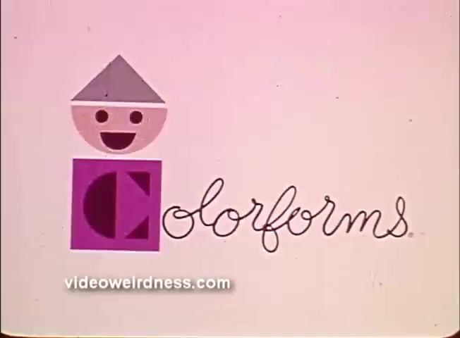 The still features a playful, abstract character made of geometric shapes, including a rounded head and a square body, topped with a triangular hat. The character has a cheerful expression. The background is a soft pink, and the word 'Colorforms' is written in a whimsical, handwritten style beside the character. This scene is likely part of the colorful and imaginative world presented in the 'Colorforms Peanuts - How's the weather Lucy?' segment, emphasizing creativity and playfulness.