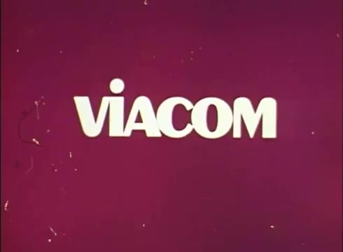 The still features the white text 'VIACOM' prominently displayed against a solid maroon background. There are visible imperfections typical of a 16mm print, such as scratches and graininess. In the lower left-hand corner, there is a small object, possibly a lab reject mark. The overall aesthetic reflects the vintage quality of the era.