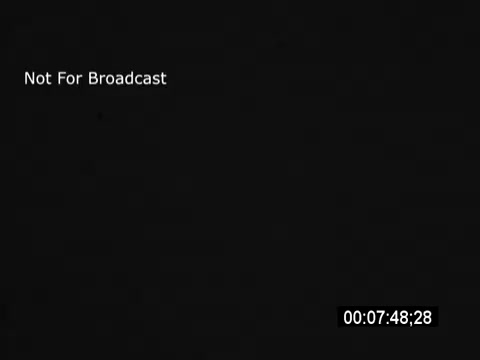 The still from the 'Pat Boone Vietnam War Era Savings Bonds PSA' features a message indicating 'Not For Broadcast.' Pat Boone discusses the benefits of investing in savings bonds during the Vietnam War era, referencing President Johnson to emphasize the importance of financial support for the country during a challenging time. The atmosphere suggests a formal and patriotic appeal to encourage public investment.