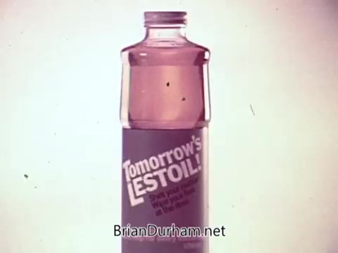 The still features a bottle of 'Tomorrow's Lestoil,' a multi-purpose cleaner. The bottle is prominently displayed, showcasing a label with the product name and a tagline. The color of the liquid inside the bottle is pink, and the background is a soft gradient, enhancing the focus on the product. This still encapsulates the essence of a musical TV commercial aimed at highlighting Lestoil's effectiveness in a visually appealing way.