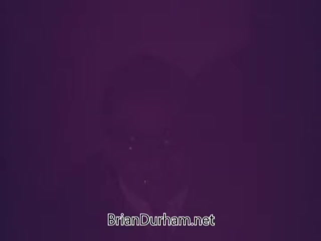 The image appears to be a still from a Heinz Baby Food commercial featuring Arte Johnson. The quality is low, resulting in a purple tint that obscures details. Arte Johnson, known for his comedic roles, likely engages in a playful or humorous presentation related to baby food, reflecting the light-hearted nature typical of commercials from that era.