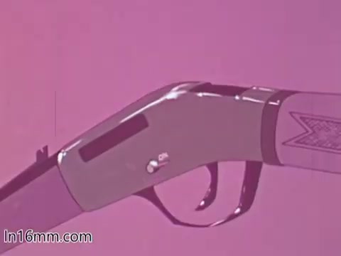 The 16mm still from the 'Blue Shield Hunting Safety PSA - 1960s' features a close-up of a hunting rifle against a pink background. The focus is on the gun's body and trigger, emphasizing its design. This visual likely aims to highlight firearm safety and responsible handling during hunting activities. The use of vibrant colors enhances the educational message of the PSA.