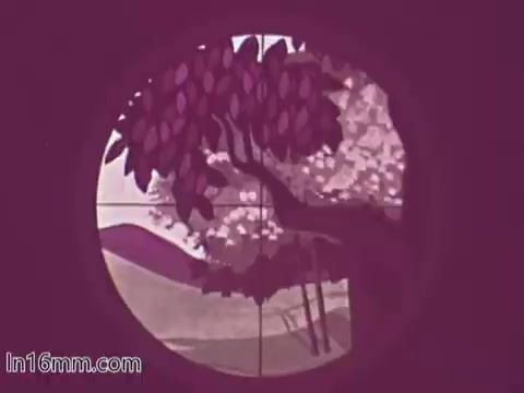 The still from the 'Blue Shield Hunting Safety PSA - 1960's' shows a view through a rifle scope, focusing on a scene that includes trees and rolling hills. The colors are muted, with a predominant purple hue, suggesting a stylized or artistic portrayal rather than a realistic depiction. This framing emphasizes the importance of safety and awareness while hunting.