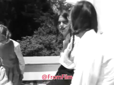 The still from 'PSA From Guideposts Magazine - 1968' likely depicts a poignant moment featuring a shy little girl from an orphanage. She appears isolated, perhaps sitting apart from other children who seem engaged with each other. The setting suggests an outdoor environment, likely emphasizing her loneliness and the social challenges she faces, being overlooked by her peers and considered a problem by adults. This visual aligns with the voice-over's narrative about her feelings of isolation and the struggles she encounters in her life.