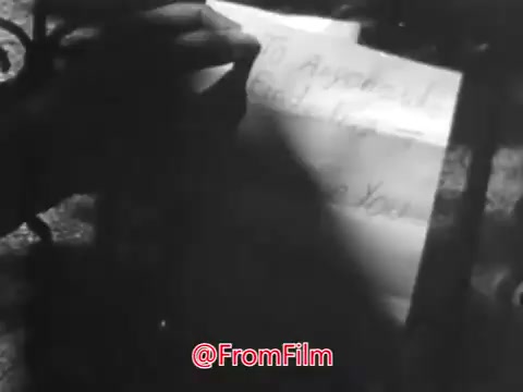 The still from 'PSA From Guideposts Magazine - 1968' depicts a hand holding a piece of paper, likely a letter. The text appears to be a message of hope or appeal, possibly addressing feelings of isolation experienced by a young girl from an orphanage. The somber context of the voice-over emphasizes her loneliness and challenges in connecting with others. Overall, the image conveys a sense of concern and the need for compassion towards children in similar situations.