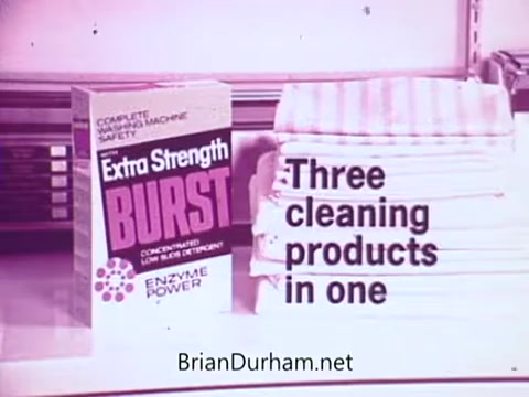 The still features a box of 'Colgate Burst' low suds laundry detergent, prominently labeled 'Extra Strength' and emphasizing its 'Enzyme Power.' Next to the box, neatly stacked are several pieces of laundry, highlighting the detergent's effectiveness. The text states, 'Three cleaning products in one,' suggesting its multifunctional capabilities. The overall presentation conveys a focus on efficiency and strength in laundry care.