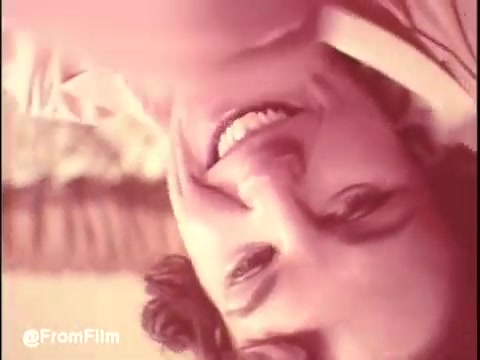 The still from 'Bounty Commercial Threaded Backwards...' shows a person with curly hair, smiling. The image is likely altered due to being spliced backwards, which might create an unusual effect. The background appears soft and out of focus, giving a nostalgic feel typical of 16mm film prints. Overall, the image conveys a lighthearted or cheerful mood, reflecting the tone of typical commercials from that era.