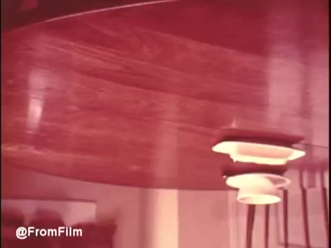 The still from 'Bounty Commercial Threaded Backwards...' features a close-up of a wooden table. The scene is likely captured at an unusual angle, with some reflective light visible, possibly from a plate or bowl positioned on the table. The coloring appears warm, typical of vintage film, suggesting a nostalgic atmosphere. The image is upside down due to the backward splicing.