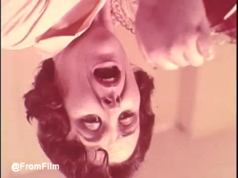 The still from 'Bounty Commercial Threaded Backwards...' features a woman with a surprised or exaggerated expression, as if reacting dramatically to something. The image is presented upside down, creating an unusual viewing experience. The color palette appears warm and slightly faded, typical of older 16mm prints. The context suggests a playful and experimental approach to film editing, using backwards playback to create a unique twist on the original commercial.