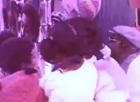 The still from 'Do it for them' - take your blood pressure medication 3 captures a lively scene with several people engaged in conversation. The colors appear vibrant, possibly evoking a sense of community and interaction. The focus seems to be on the importance of taking medication for health, emphasizing support among individuals.