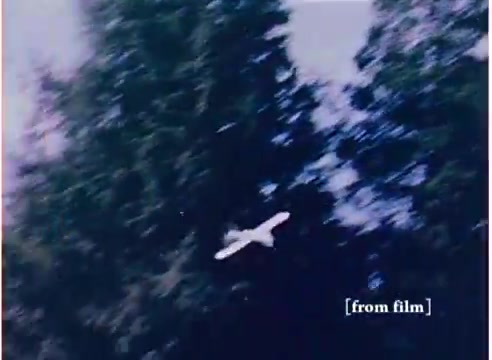The still from the 'Flying Submarine' toy commercial features a white toy resembling a submarine, depicted flying through a vibrant, outdoor setting filled with tall greenery. The film, dated 1972, highlights a whimsical concept of a toy capable of flying, aligning with the playful tone of toy advertisements from that era. The presence of separate soundtracks, including a labeled 'good' version, indicates efforts to ensure quality in production, while also hinting at possible challenges with audio in the other version marked 'DO NOT USE'.