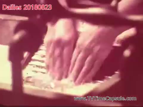 The still depicts a close-up of hands playing a keyboard or piano with a warm, vintage color tone. The focus is on the hands, emphasizing the act of playing, while the surroundings are softly blurred.