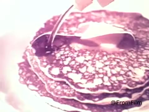 The still features a close-up shot of a stack of pancakes being drizzled with syrup. The warm tones highlight the golden brown of the pancakes and the glossy, rich texture of the syrup as it cascades down the sides. This 16mm print captures the nostalgic essence of breakfast, emphasizing the delicious appeal of Golden Griddle Pancake Syrup from the 1970s.