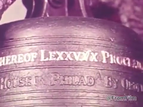 The still features a close-up of the Liberty Bell, focusing on its inscription and details of the bell's surface. The image likely conveys a solemn tone, emphasizing its historical significance as a symbol of liberty. The warm color palette suggests a nostalgic or poignant atmosphere, aligning with the voiceover's message about ongoing oppression and the interconnectedness of freedom.