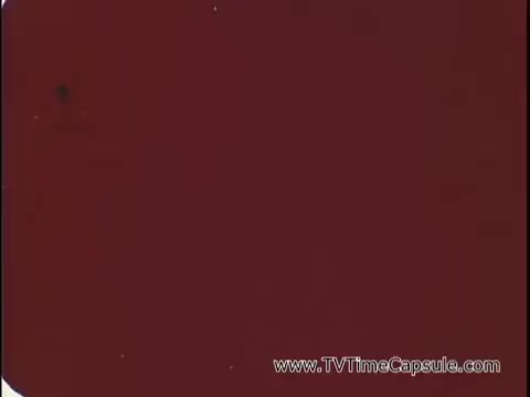 The still captures a moment from a 1969 advertisement for Lasting Beauty makeup finish. It features David Lawrence, a renowned makeup artist, demonstrating a makeup application process. The scene likely emphasizes the effectiveness and appeal of the product, highlighting its promise of longevity in wear. The voiceover suggests a direct engagement with viewers, especially targeting women, as he instructs them to close their eyes, indicating a hands-on approach to showcasing the makeup's application.