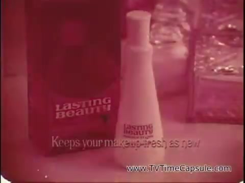 The still features a vintage advertisement for 'Lasting Beauty' makeup finish from 1969. The product is displayed prominently in a white bottle with a minimalist design, next to its packaging. The voiceover highlights the expertise of makeup artist David Lawrence, emphasizing the need for makeup to maintain its appearance. The overall aesthetic is reminiscent of late 1960s advertising, with soft colors and a focus on beauty and femininity.