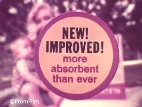The still features a colorful graphic, prominently displaying the words 'NEW! IMPROVED! more absorbent than ever' within a circular design. In the background, there's a soft-focus image of a woman holding a baby, indicative of the familial themes common in 1970s diaper advertisements. The overall aesthetic reflects the vintage style of the era, set against a backdrop of what appears to be outdoor greenery. This captures the essence of a nostalgic commercial aimed at promoting Pampers' enhanced product features.   Follow us on Twitter @FromFilm.