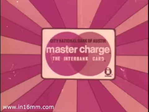 The still features a graphic design centered around the MasterCharge card, prominently displaying its logo. The background is a vibrant, radial pattern in shades of pink, enhancing the visual appeal. The text includes 'City National Bank of Austin' and 'Master Charge - The Interbank Card,' emphasizing the card's link to the bank. This presentation is typical of animated commercials aimed at promoting banking services, specifically highlighting the overdraft protection feature.