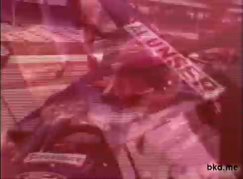 The still appears to be a 16mm print of racing footage featuring Al Unser and Mario Andretti, likely from a practice session at the Indianapolis Motor Speedway during the late 1960s. The image is characterized by a vintage aesthetic, typical of that era, with visible grain and color shifts. The focus on the drivers indicates the intensity of preparations prior to a race, capturing the atmosphere of the time. Unfortunately, it lacks sound, which would have enhanced the experience.