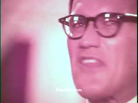 The still features a middle-aged man wearing thick black glasses, with an expressive facial demeanor suggesting enthusiasm or urgency. The color tone of the image appears warm, potentially indicating a vintage aesthetic from the 1970s. The backdrop is somewhat blurred, placing emphasis on the man's animated delivery, likely promoting a deal or game show format related to United Airlines. The overall atmosphere reflects the energetic style typical of commercials from that era.